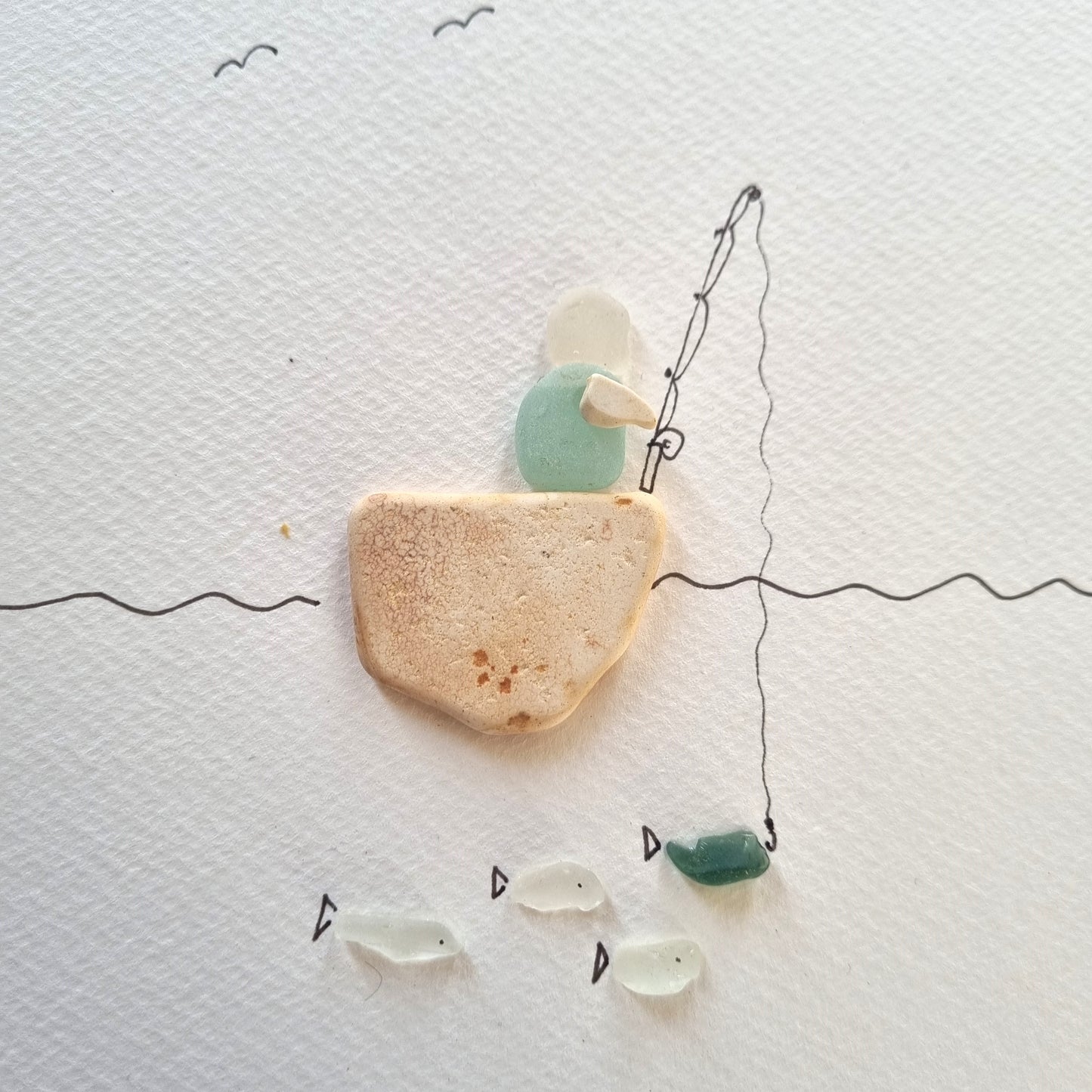 Seaglass artwork of a person on a boat fishing with fish