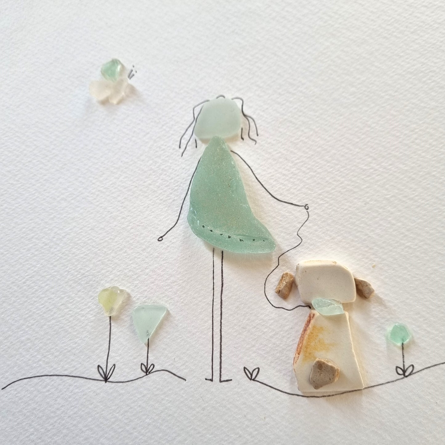 Seaglass artwork of a lady and her dog out for a walk
