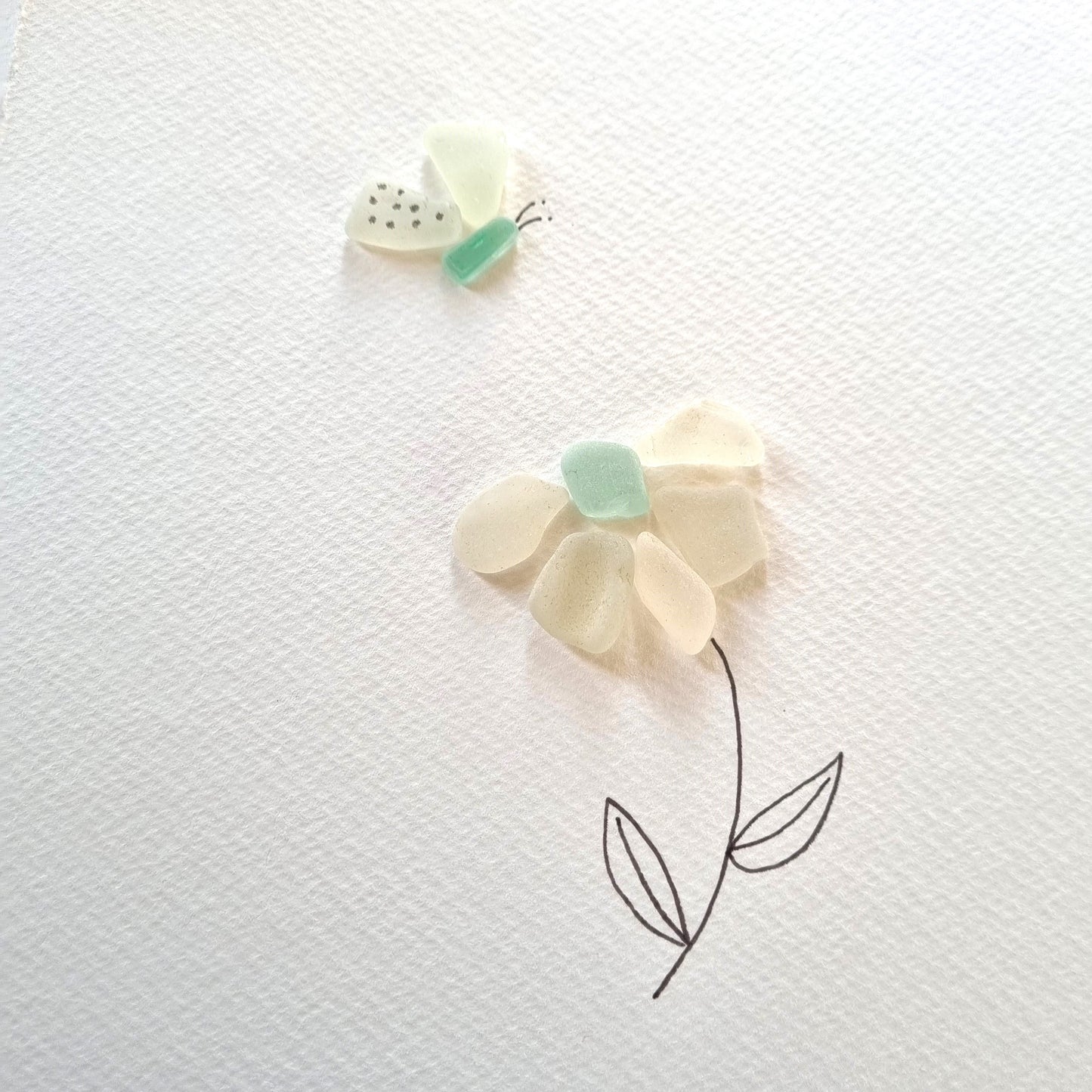 Seaglass artwork of a flower and butterfly